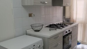 Een kleine keuken met een wasmachine, een fornuis en een magnetron.