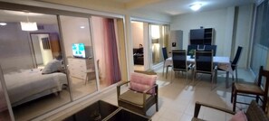 A modern living room with a sofa, a dining table with chairs, and a TV in the background.