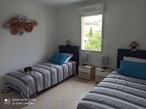 A bedroom with two beds, a window, and a decorative wall piece.
