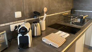 Een moderne keuken met een roestvrijstalen fornuis, een waterkoker, een broodrooster en een spoelbak met afwasschaal.