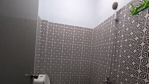 Kylpyhuone, jossa on wc, suihku ja kuviollinen seinä.