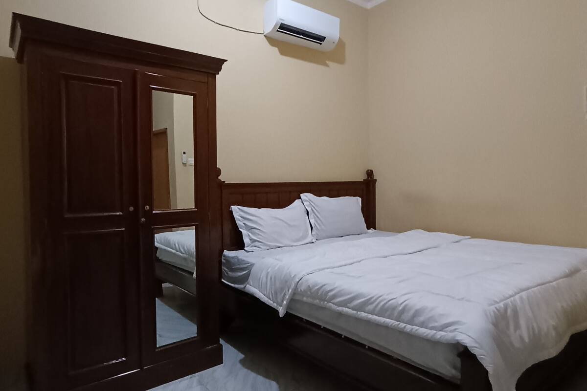 Une chambre à coucher comprenant un lit, une armoire et un appareil de climatisation.