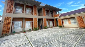 A two-story building with a flat roof, large windows, and a paved courtyard. - Hotel O Ananda Homestay Syariah (Pekanbaru)