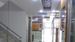 A corridor with a patterned ceiling, a staircase on the left, and a wooden wall on the right. - Hotel Prime Inn Mirpur 10 (Dhaka)
