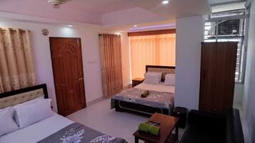 Une chambre d’hôtel avec deux lits, une porte en bois et une fenêtre avec des stores.