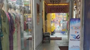 A corridor with a store on the left displaying mannequins in colorful clothing. A sign above reads "PINK" and another sign in a foreign language is visible. - Hotel Prime Inn Mirpur 10 (Dhaka)