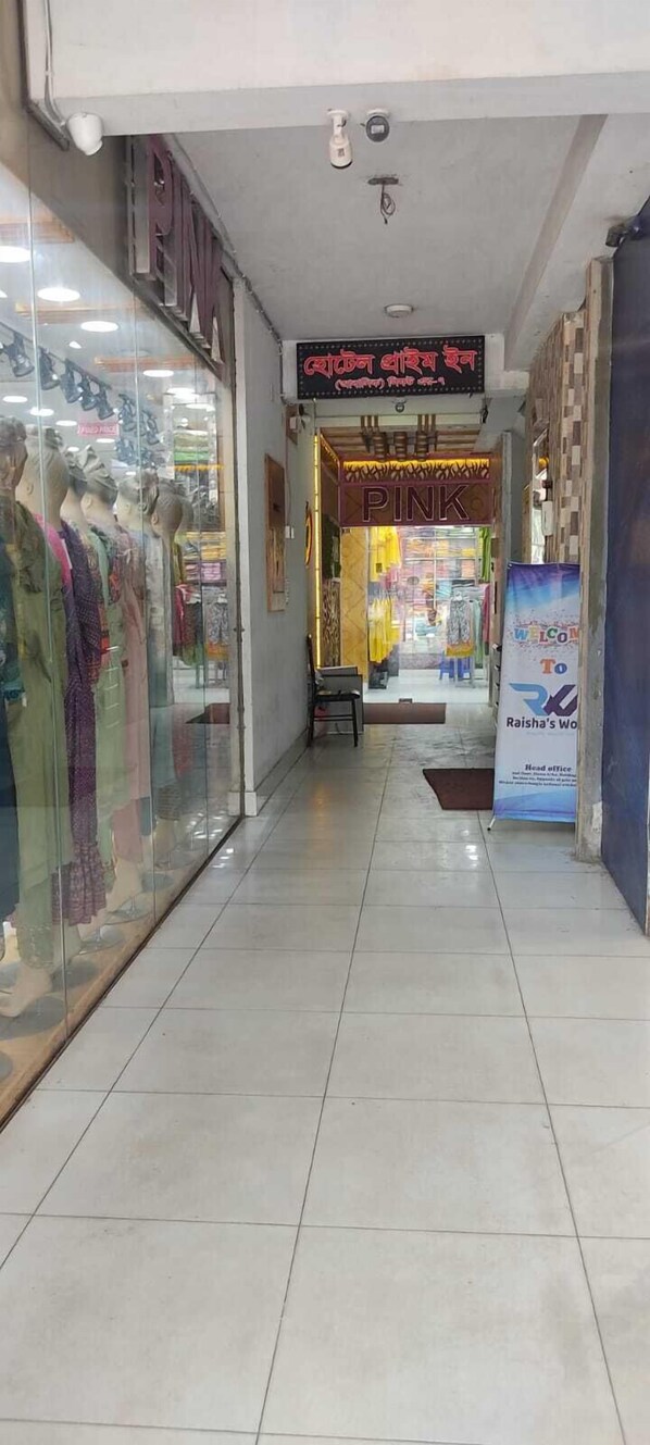 A corridor with a store on the left displaying mannequins in colorful clothing. A sign above reads "PINK" and another sign in a foreign language is visible.