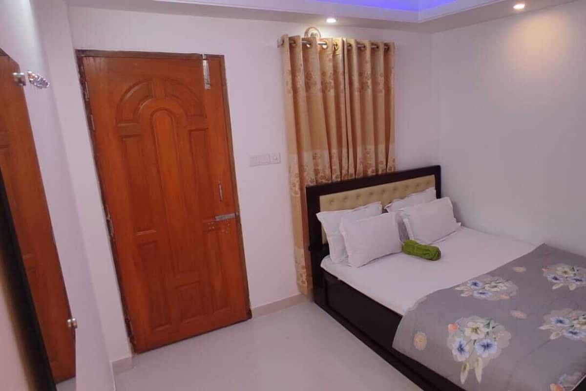 A bedroom with a wooden door, a bed with white bedding, and a floral-patterned bedspread.