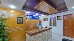 A reception area with a wooden reception desk, a blue illuminated sign, and framed artwork on the walls. - Hotel Prime Inn Mirpur 10 (Dhaka)