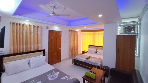 A hotel room with a bed, a desk, a chair, a wardrobe, and a ceiling fan. - Hotel Prime Inn Mirpur 10 (Dhaka)