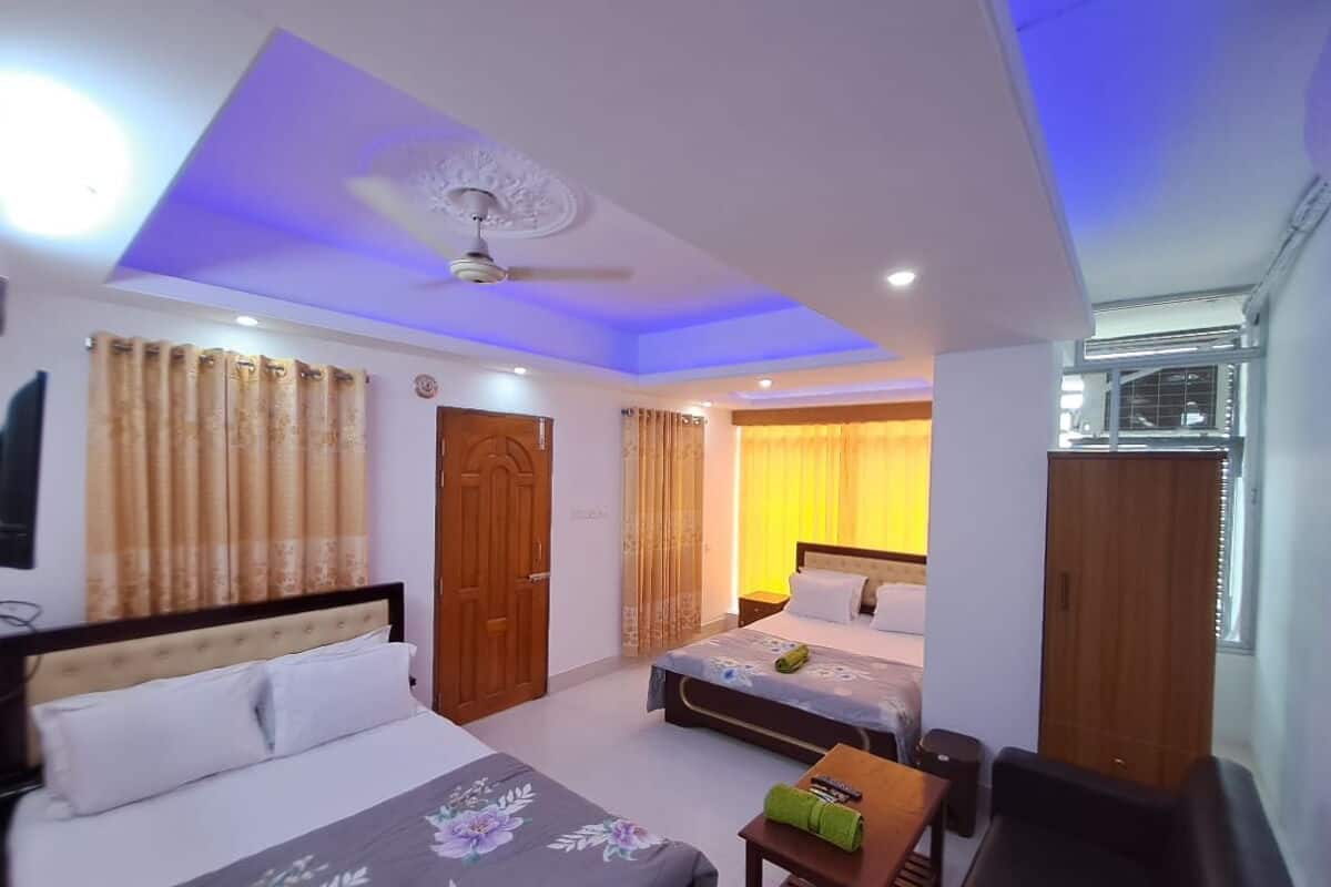 A hotel room with a bed, a desk, a chair, a wardrobe, and a ceiling fan.