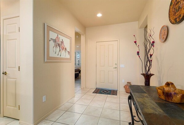 A hallway with a door, a framed artwork, a vase with branches, and a textured table.
