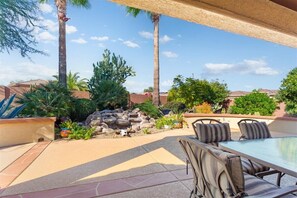 An outdoor patio area with a glass-top table and striped cushioned seating.