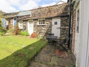 A stone cottage with a small garden, a white door, and a table with chairs outside. - Fell View (Ambleside)