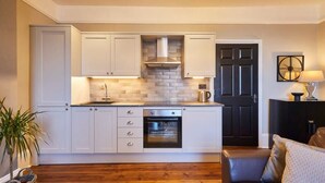 Una cocina moderna con armarios blancos, horno integrado y puerta negra.