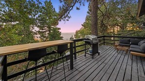 Een houten terras met een barbecue, zithoek en uitzicht op het meer.