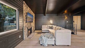 Een moderne woonkamer met een stenen open haard, een groot raam en een modulaire bank.