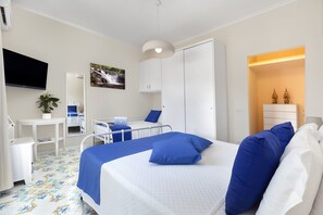 Une chambre d’hôtel comprenant un lit, une table de chevet, une chaise, un bureau et un téléviseur.