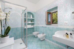 Une salle de bain équipée d’une douche, de toilettes, d’un bidet et d’un lavabo.