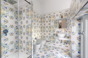 A bathroom with patterned tiles, a sink, a bidet, and a mirror.