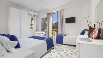 Camera d'albergo con un letto, una scrivania con un portatile, un telefono, una televisione e un balcone con vista sull'esterno.