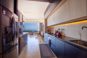 A modern kitchen with a view of the ocean, a dining area with a table and chairs, and a large window.