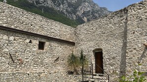 A stone building with a pool, outdoor seating, and a mountainous backdrop. - Villa del Lis (Gargnano)