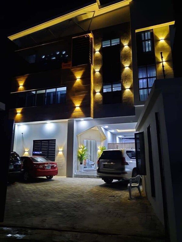 A modern building with a well-lit entrance, a covered car parking area, and a visible staircase leading to the upper floors. - Sublime Hotel Lekki  (Lekki)