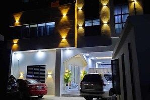 A modern building with a well-lit entrance, a staircase, and parked cars. - Sublime Hotel Lekki  (Lekki)