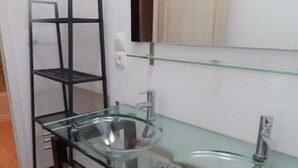 A bathroom with a glass sink, a black metal shelf, and a mirror above the sink. - Les Deux Tours (Aiguèze)