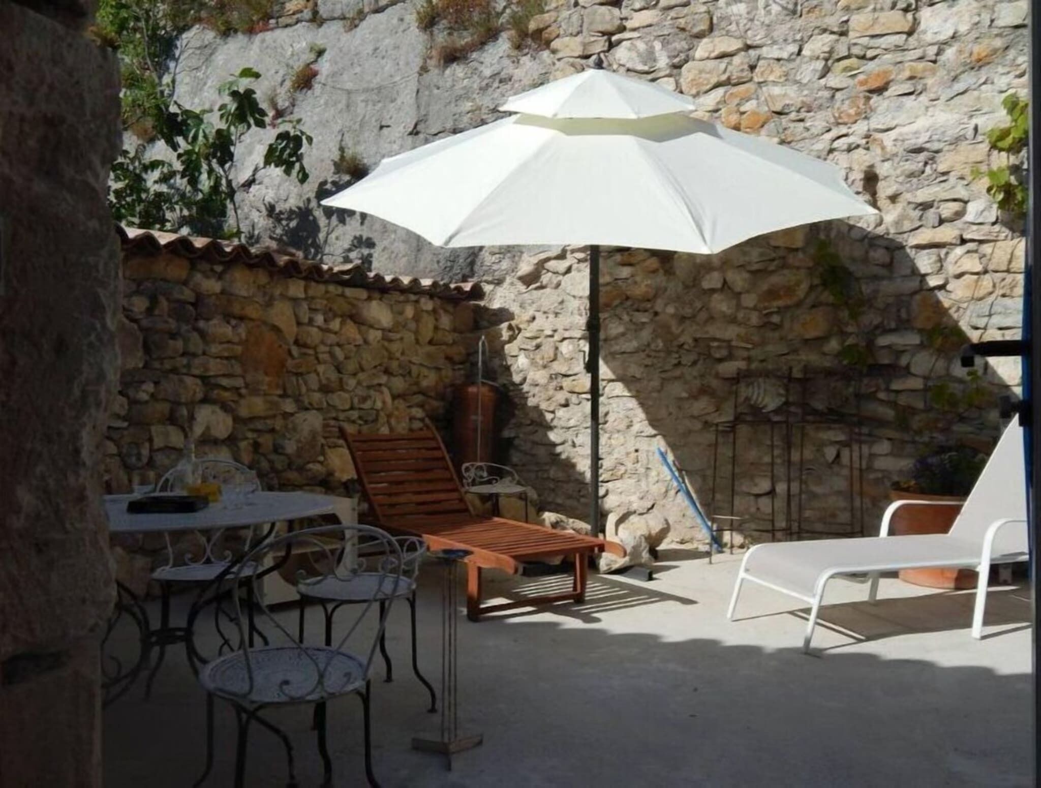 A stone wall patio with outdoor furniture, including a table, chairs, and a wooden bench.