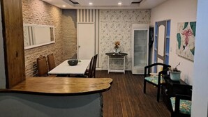A dining area with a wooden table and chairs, a stone wall, and a patterned wallpaper wall. - Hermosa Casona Central (Montevideo)