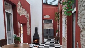 A narrow outdoor corridor with a checkered floor, a round wooden table with chairs, and a brick fireplace. - Hermosa Casona Central (Montevideo)