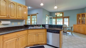 A spacious kitchen with wooden cabinets, a dishwasher, and a dining area with a table and chairs.