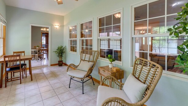A spacious room with a dining area, wicker chairs, and large windows.
