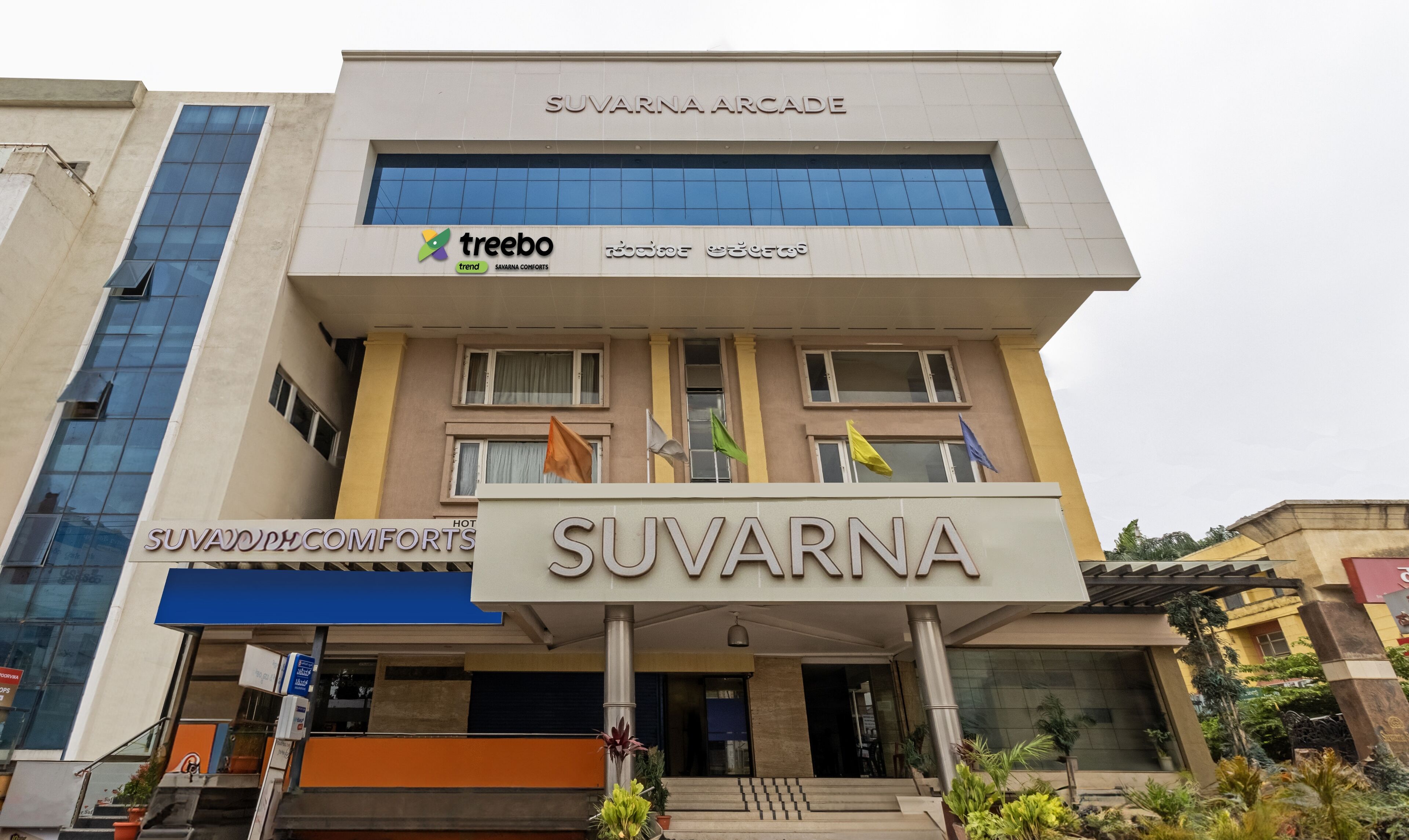 A hotel named Suvarna Arcade with a modern facade, featuring a prominent sign and a logo for Treebo.