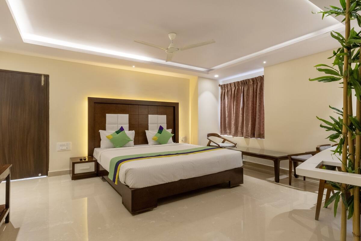 A modern hotel room with a large bed, bedside tables, a desk, and a ceiling fan.