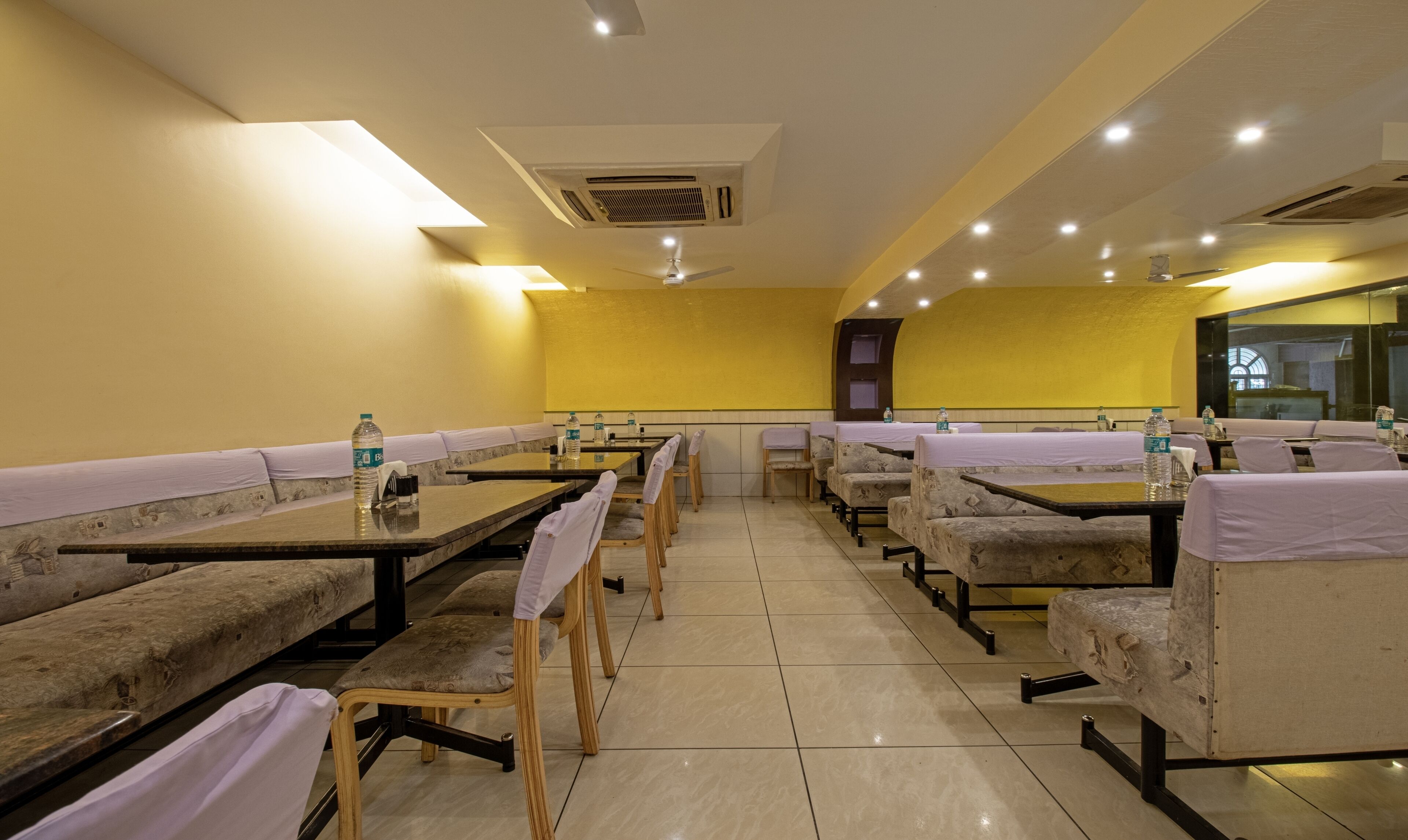 A dining area with booths and tables, equipped with water bottles, and a ceiling fan.