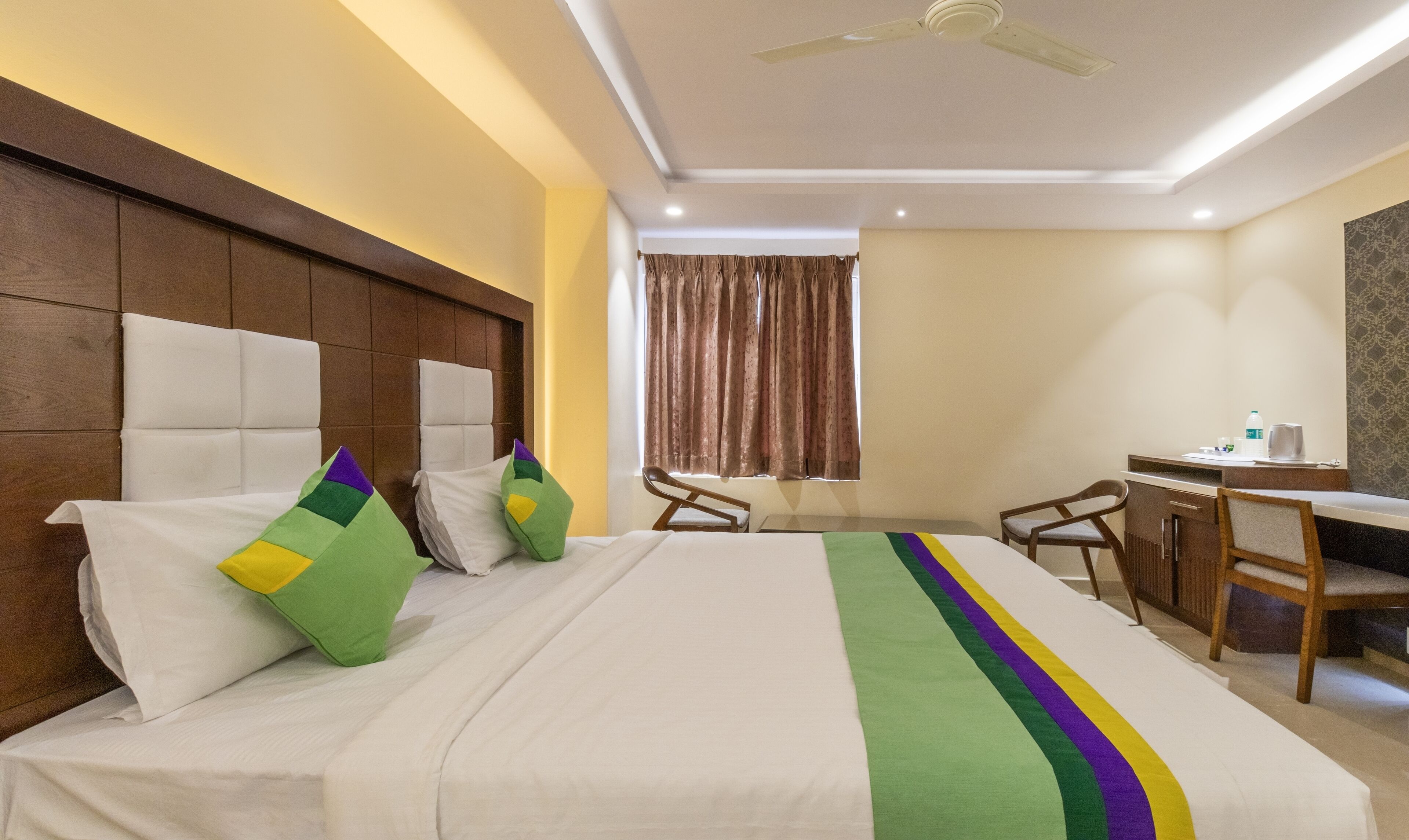 A hotel room with a large bed, a desk, and a chair.
