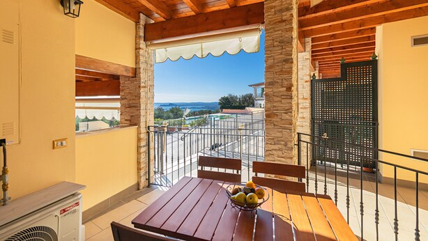 Ein Balkon mit Holztisch, Stühlen und einer Obstschale.