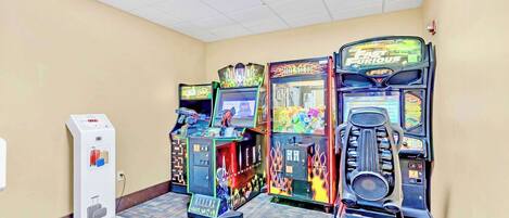 A row of arcade games in a hallway with a scale for weighing luggage.