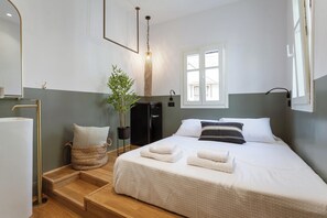 A neatly arranged hotel room with a bed, bedside table, lamp, and a window.