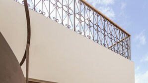 Un immeuble avec une enseigne indiquant « selana, studio de luxe confortable », un escalier, un balcon doté d’une rambarde en métal et un appareil de climatisation.