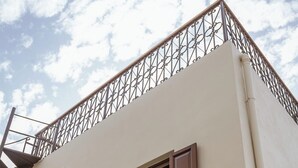 Un bâtiment doté d’un balcon, d’un escalier et d’une fenêtre avec des volets.