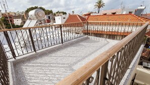 Une terrasse sur le toit, dotée d’un sol à motifs, de rampes en métal et offrant une vue sur les bâtiments environnants.
