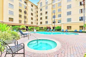 Une cour d’hôtel avec une piscine, des chaises longues et un jacuzzi.