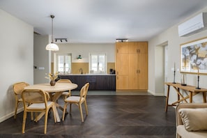 Eine moderne Küche mit dunklem Holzboden, einem Essbereich mit Korbstühlen und einem großen Holzschrank.