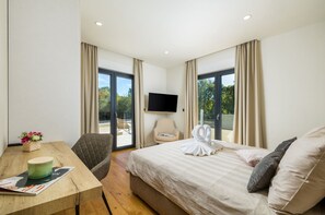 A hotel room with a bed, a desk with a chair, a television, and a balcony with a chair.