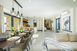 A modern living room with a sofa and a dining area with a table set for four.