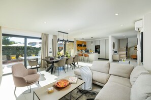 A modern living room with a sofa, coffee table, and dining area with chairs and a table.